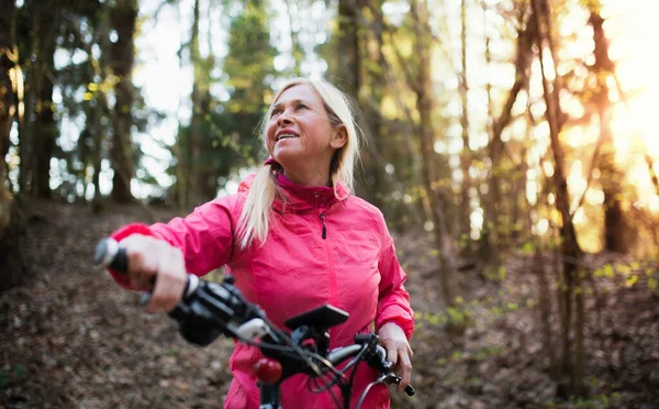 Aktive Seniorin mit E-Bike in der Natur unterwegs. — Stockfoto