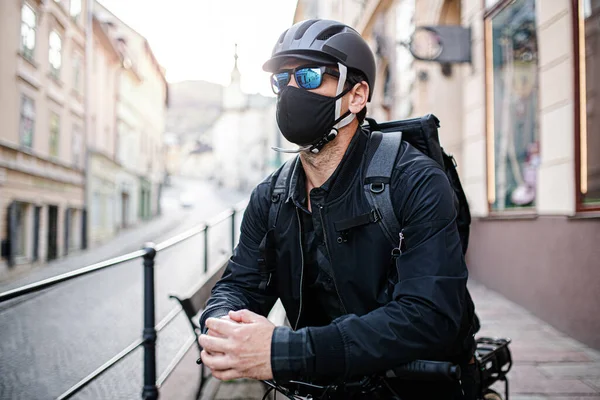 Entrega mensageiro homem com máscara facial e bicicleta entregando parcelas na cidade . — Fotografia de Stock