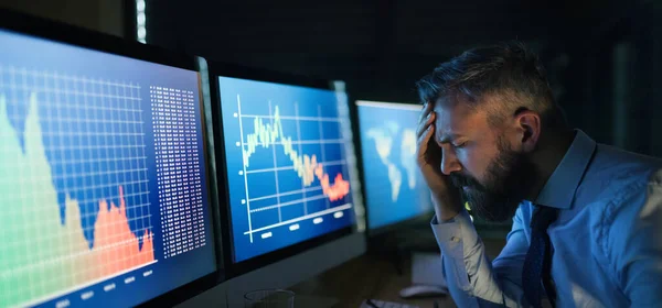 Empresário frustrado com computador sentado à secretária, a trabalhar até tarde. Conceito de crise financeira . — Fotografia de Stock