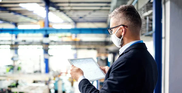 Technik nebo inženýr s ochrannou maskou a tabletem pracující v průmyslové továrně. — Stock fotografie