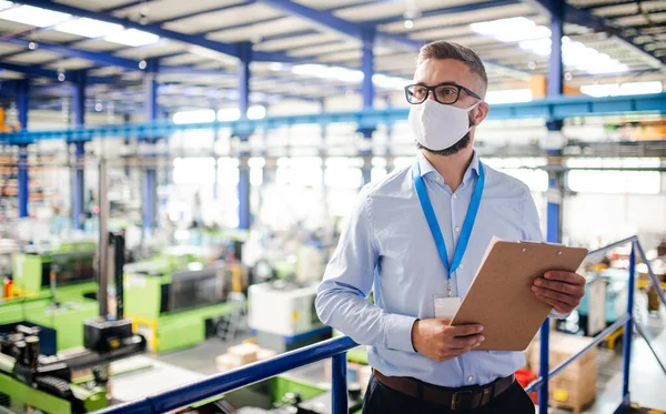 Műszerész vagy mérnök ipari üzemben dolgozó védőmaszkkal, álló. — Stock Fotó