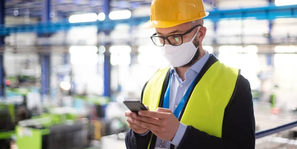 Técnico ou engenheiro com máscara protetora e telefone em fábrica industrial . — Fotografia de Stock