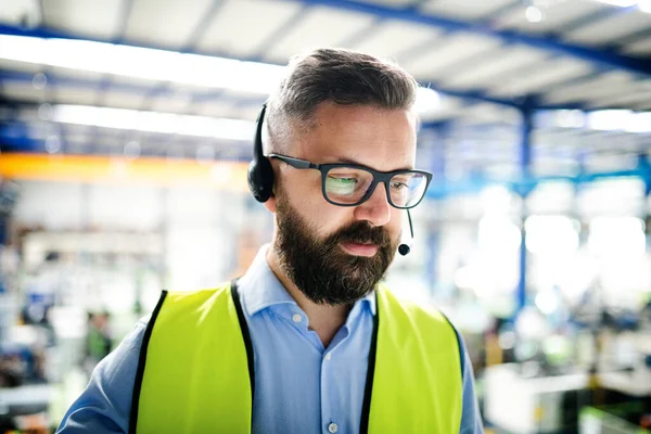 Vista frontal do técnico ou engenheiro com fone de ouvido em pé na fábrica industrial . — Fotografia de Stock