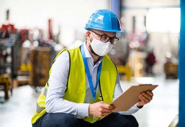 Műszerész vagy mérnök ipari üzemben dolgozó védőmaszkkal és sisakkal. — Stock Fotó