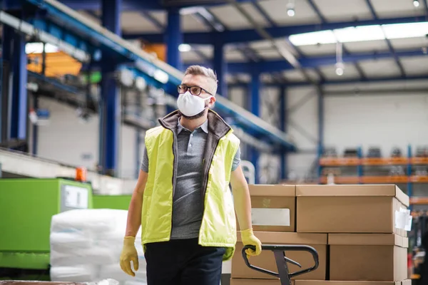 Werknemer met beschermend masker werkzaam in industriële fabriek of magazijn. — Stockfoto