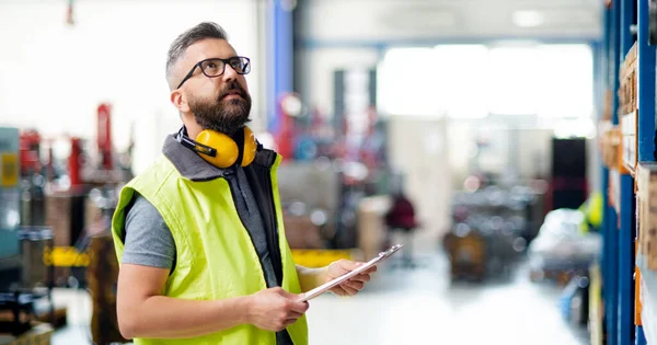 Technik nebo inženýr s ochrannými sluchátky stojící v průmyslové továrně. — Stock fotografie