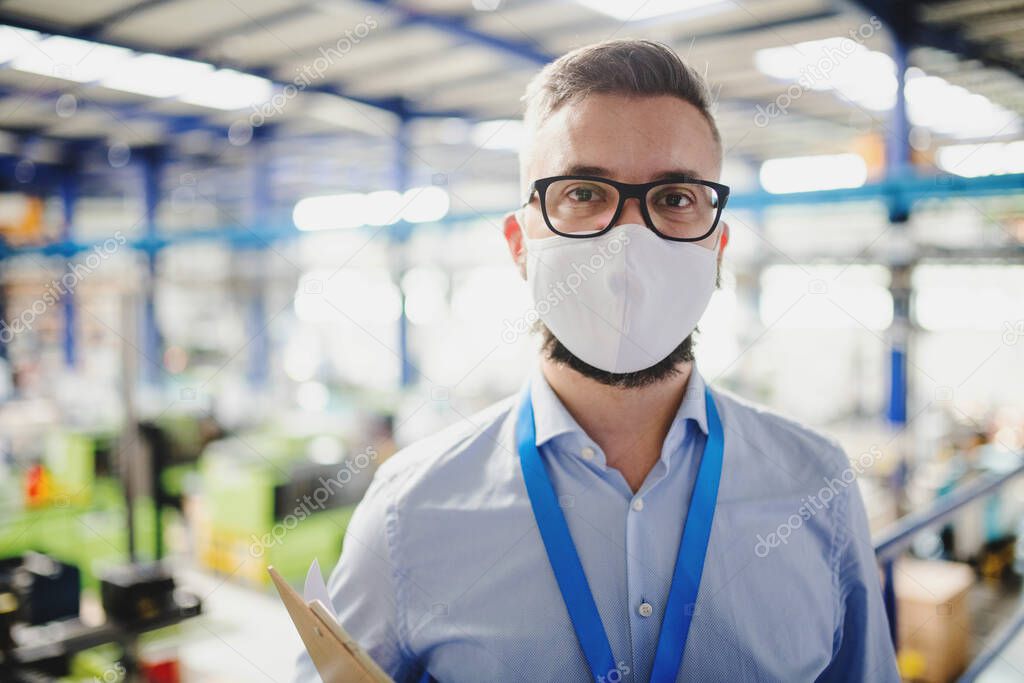 Technician or engineer with protective mask working in industrial factory, standing.