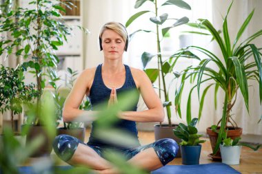 Evde yoga yapan genç bir kadının ön görüntüsü..