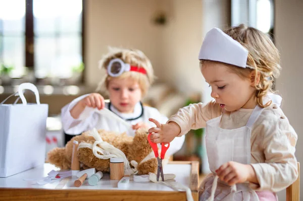 Due bambini piccoli con uniformi da medico in casa, che giocano . — Foto Stock