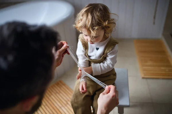 Father putting bandage on small hurt toddler child indoors at home. — Stock Photo, Image