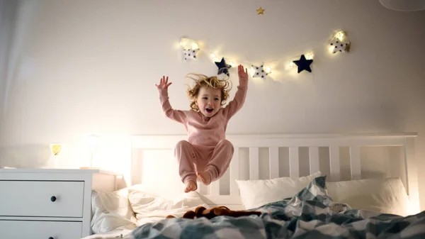 Dos niños pequeños saltando en la cama en casa, divirtiéndose . — Foto de Stock