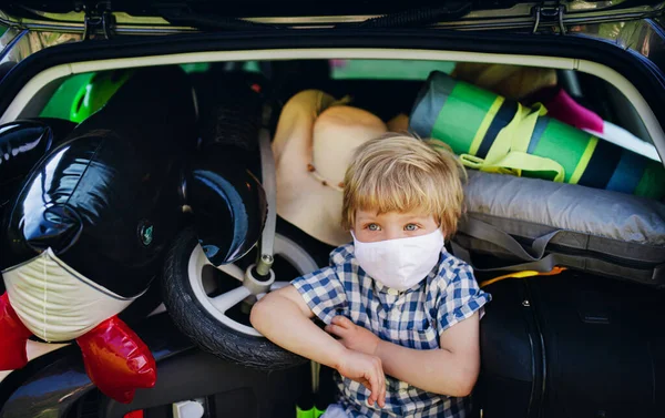 Niño pequeño con máscara facial sentado en la bota de coche cargado en el campo, concepto de viaje local . —  Fotos de Stock