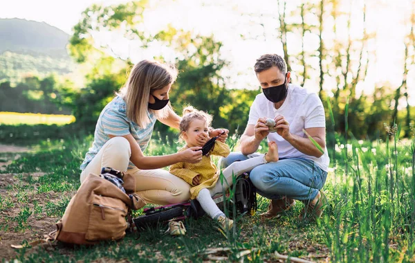 Familj med liten dotter på cykeltur, bär ansiktsmasker. — Stockfoto