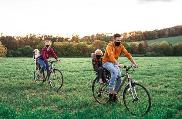 Familie mit zwei kleinen Kindern auf Radtour, mit Mundschutz. — Stockfoto