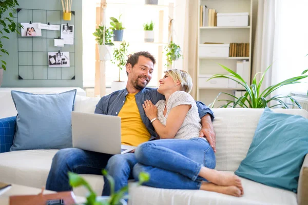 Glada par förälskade sitter hemma, med laptop. — Stockfoto