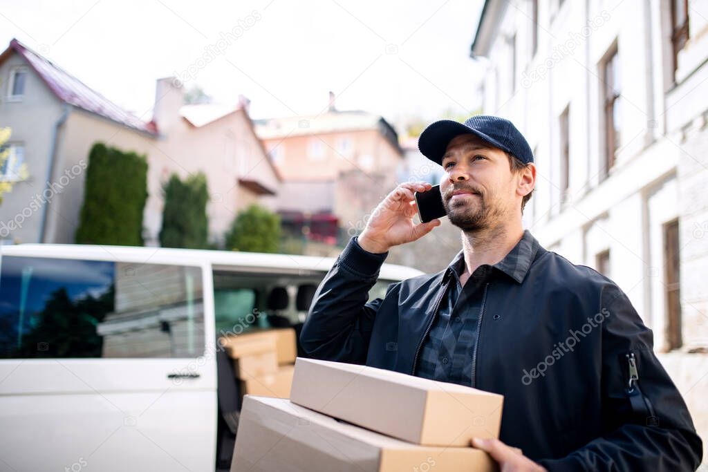 Delivery man courier delivering parcel box in town using smartphone.