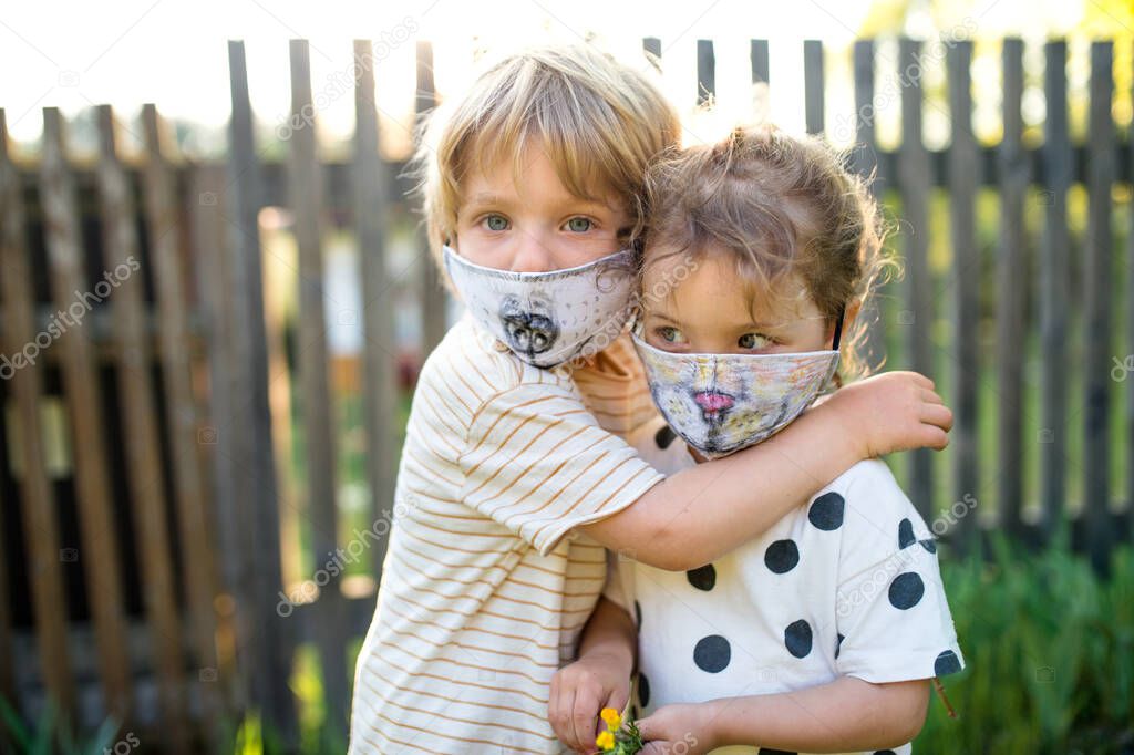 Small children with face masks playing outdoors, coronavirus concept.