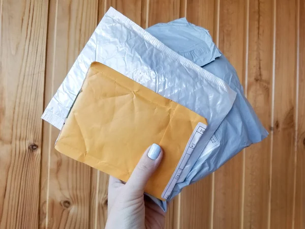 Tres paquetes postales paquete pequeño blanco, gris y amarillo en la superficie de fondo de madera — Foto de Stock