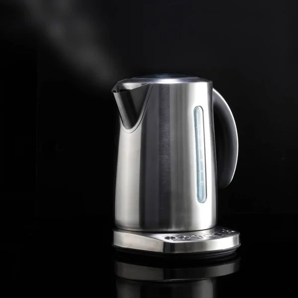 Modern kettle with steam on black reflective surface — Stock Photo, Image