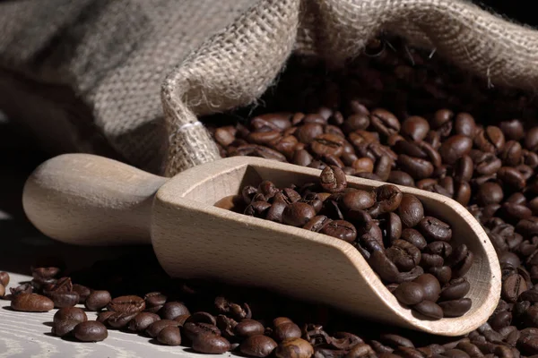 Granos de café en una cucharada con bolsa hessian — Foto de Stock