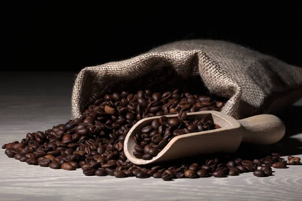 Granos de café en una superficie de madera con una cucharada y saco de hessian — Foto de Stock