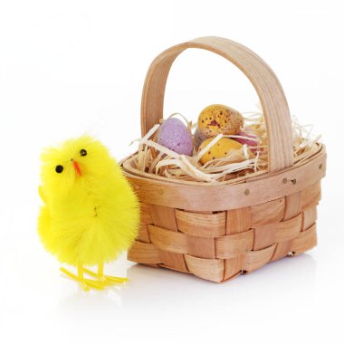 Paskalya pilici ve şeker yumurtaları sepetin içinde samanla beyaz