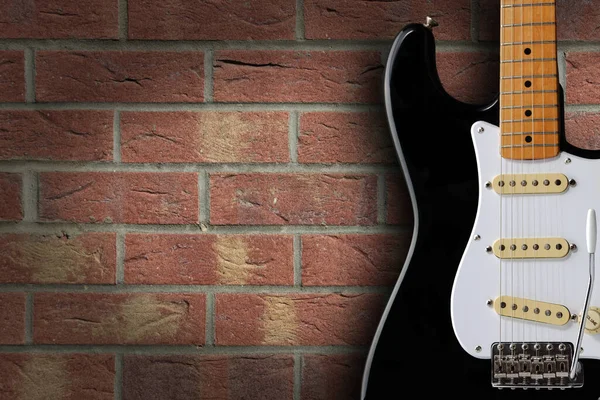 Retro černá a bílá elektrická kytara na cihlovém pozadí s kopírovacím prostorem — Stock fotografie