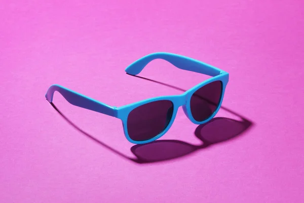 Синие солнцезащитные очки на розовом фоне с тенью — стоковое фото