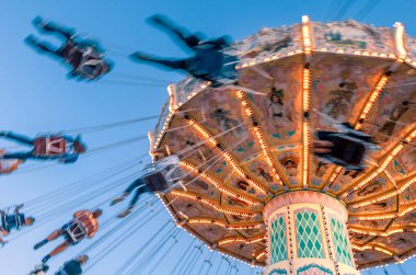 Eğlence parkı hareketi, geçmişe dönük vintage salıncakta açık mavi gökyüzüne doğru sürücüler bulanıklaştırdı.