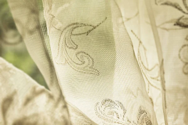 Staromódní čirá tkanina vzorovaný závěs visí na okně v přirozeném světle — Stock fotografie