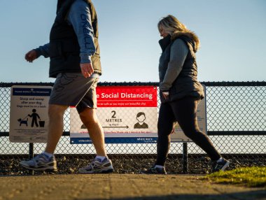 White Rock, Kanada - 25 Mart 2020: Covid-19 sosyal uzaklık bildirimini yürüyerek geçen yayalar