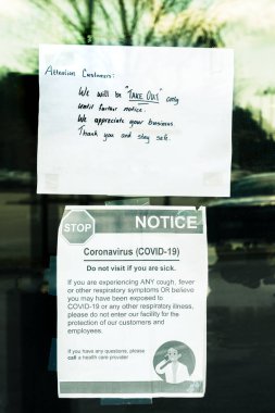 Take-out only and Covid-19 health signs taped to door of restaurant during time of Coronavirus pandemic clipart