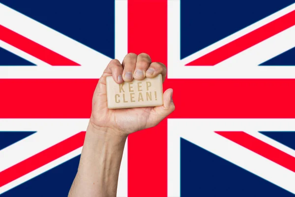 Biały mężczyzna trzyma mydło za rękę ze zwrotem: Keep Clean, na tle brytyjskiej flagi Obrazek Stockowy