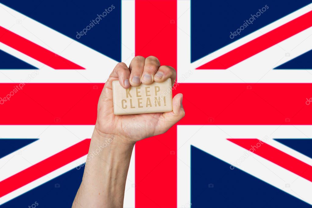 Caucasian male hand holding soap with phrase: Keep Clean, against British flag background