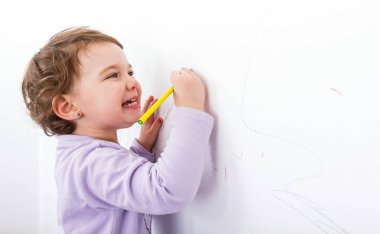 Adorable child drawing on the wall clipart