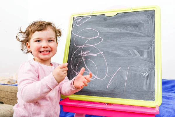 Little girl drawing on blackboard Stock Picture