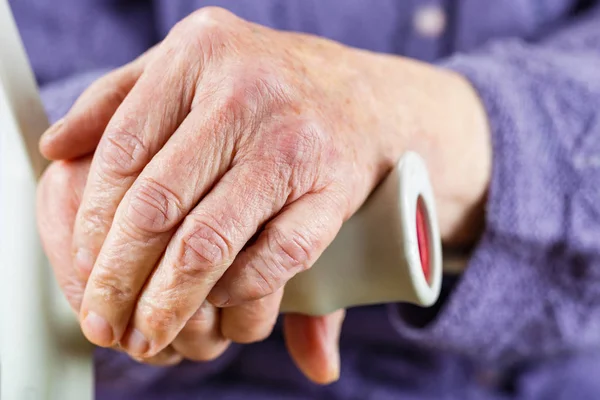 Elderly hands resting on stick — Stock Photo, Image