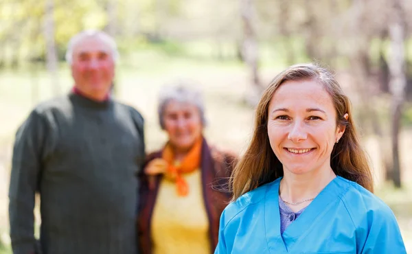 Yaşlı çift ve genç caregiver — Stok fotoğraf