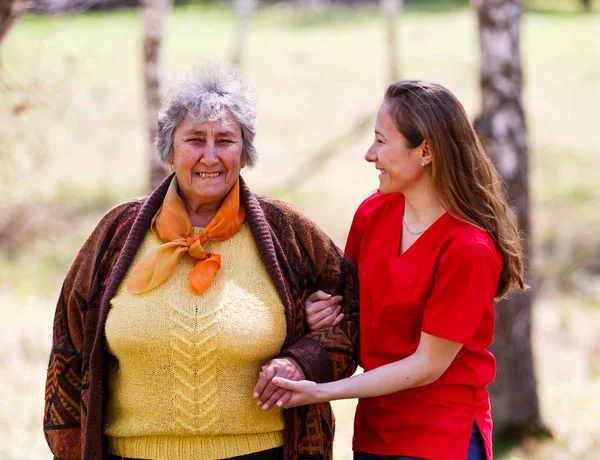 Ältere Frau und junge Pflegekraft — Stockfoto