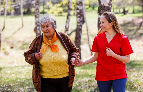 Ältere Frau und junge Pflegekraft — Stockfoto