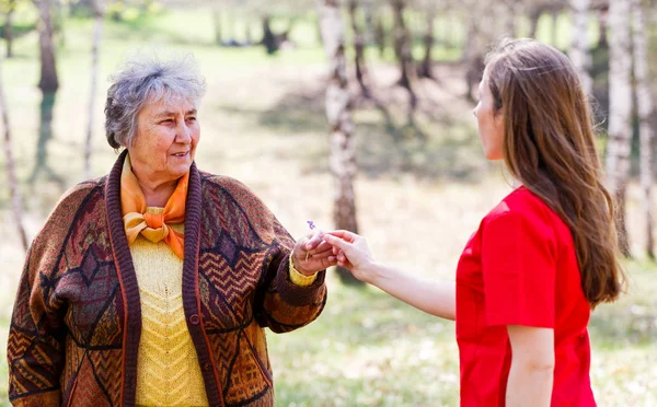 Yaşlı çift ve genç caregiver — Stok fotoğraf