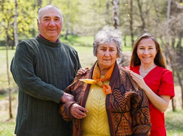 Bejaarde echtpaar en jonge mantelzorger — Stockfoto