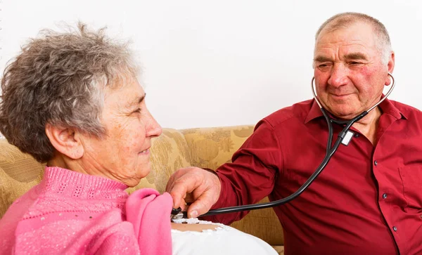 Пожилой человек слушает сердцебиение жены — стоковое фото