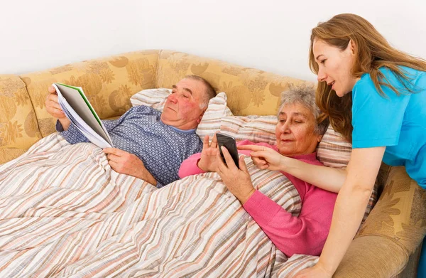 Elderly couple and young caregiver — Stock Photo, Image