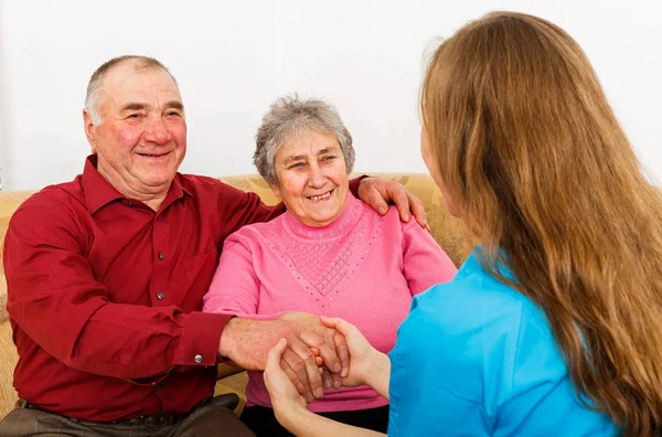 Smiling elderly couple and young caregiver — Stock Photo, Image