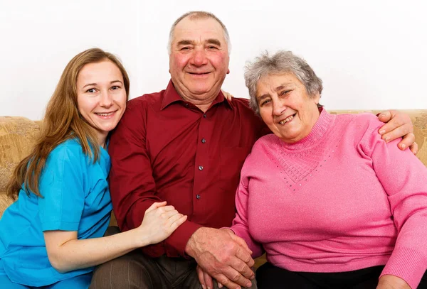 Smiling elderly couple and young caregiver — Stock Photo, Image