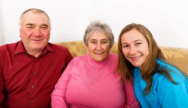 Happy elderly couple and young caregiver — Stock Photo, Image