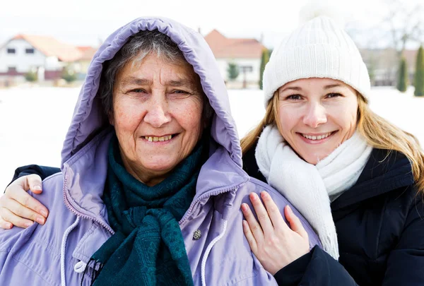 Mujer anciana sonriente y cuidadora joven — Foto de Stock