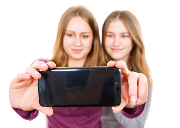 Hymyilevät nuoret sisaret ottavat selfien — kuvapankkivalokuva