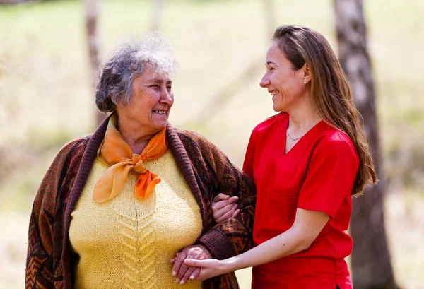 Ältere Frau und junge Pflegekraft — Stockfoto